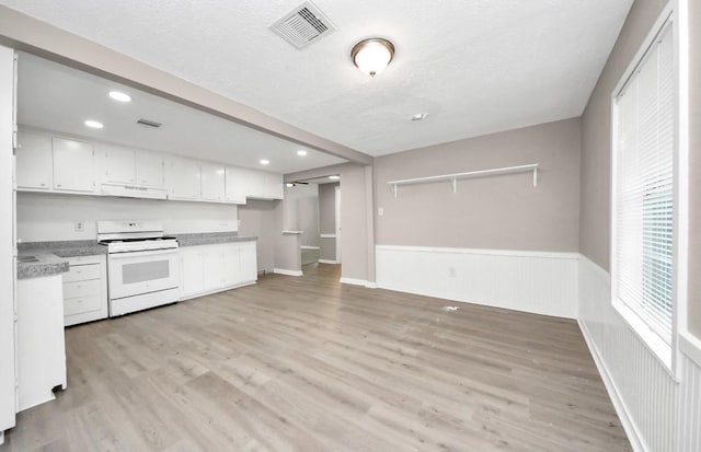 720 Roosevelt St, La Marque, TX 77568 - kitchen with gas range gas stove, under cabinet range hood, white cabinets, light wood-style floors, and wainscoting