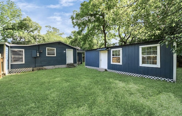 720 Roosevelt St, La Marque, TX 77568 - back of house featuring entry steps, a lawn, and an outbuilding