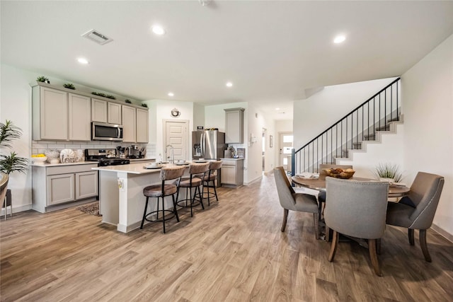 14714 Sweet Water Dr, Baytown, TX 77523 - kitchen featuring stainless steel appliances, gray cabinetry, a kitchen bar, backsplash, and recessed lighting