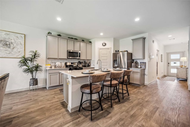 14714 Sweet Water Dr, Baytown, TX 77523 - kitchen with appliances with stainless steel finishes, gray cabinets, light wood finished floors, tasteful backsplash, and recessed lighting
