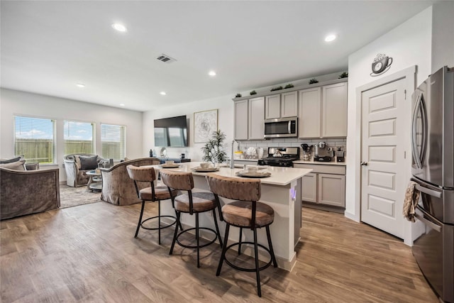 14714 Sweet Water Dr, Baytown, TX 77523 - kitchen featuring stainless steel appliances, a kitchen breakfast bar, open floor plan, gray cabinets, and light countertops