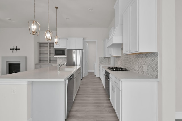 10066 Preserve Way, Conroe, TX 77385 - kitchen with appliances with stainless steel finishes, light wood-style floors, a sink, decorative backsplash, and light countertops