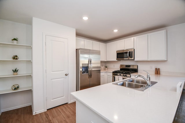 9315 Sierra Point Way, Baytown, TX 77521 - kitchen with appliances with stainless steel finishes, a sink, a peninsula, light wood finished floors, and white cabinetry