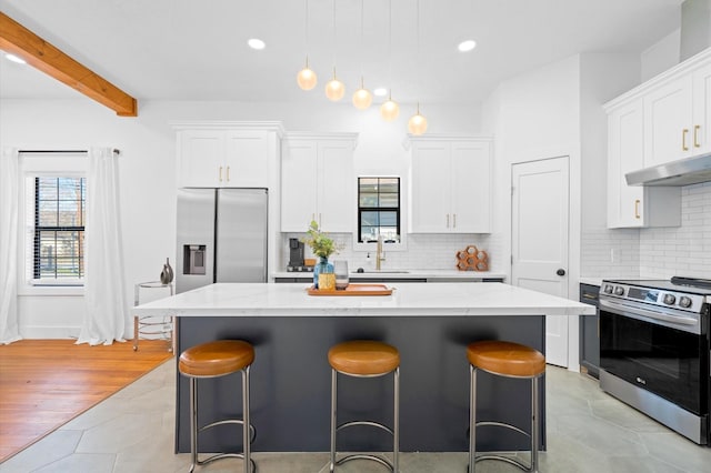 128 N Jenkins St, Houston, TX 77003 - kitchen with stainless steel appliances, under cabinet range hood, a sink, a center island, and a kitchen breakfast bar