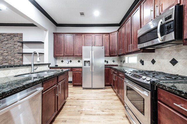 2503 Dallas St, Houston, TX 77003 - kitchen with stainless steel appliances, a sink, ornamental molding, light wood-style flooring, and dark stone countertops