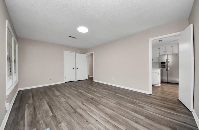 2013 15th Ave N, Texas City, TX 77590 - unfurnished bedroom with stainless steel refrigerator with ice dispenser, wood finished floors, a textured ceiling, and baseboards