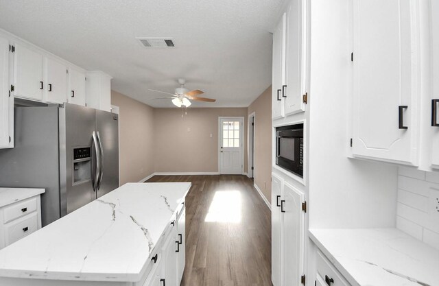 2013 15th Ave N, Texas City, TX 77590 - kitchen featuring stainless steel refrigerator with ice dispenser, black microwave, a ceiling fan, wood finished floors, and white cabinets