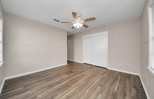 2013 15th Ave N, Texas City, TX 77590 - unfurnished bedroom with wood finished floors, a closet, a wainscoted wall, a ceiling fan, and baseboards