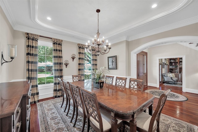 dining room with arched walkways, a chandelier, a raised ceiling, wood finished floors, and ornamental molding