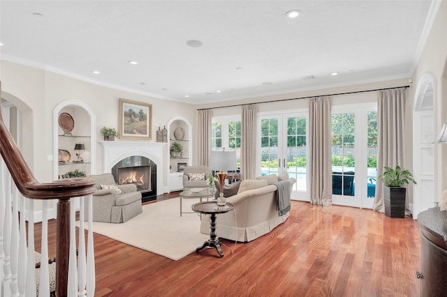 living room featuring french doors, light wood-style floors, healthy amount of natural light, a high end fireplace, and ornamental molding