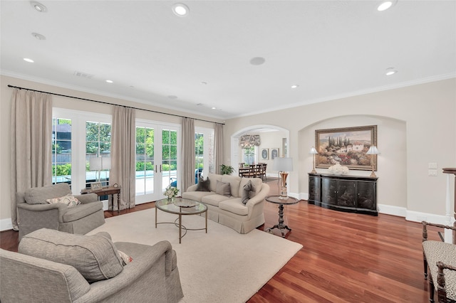 living area with arched walkways, ornamental molding, wood finished floors, baseboards, and recessed lighting