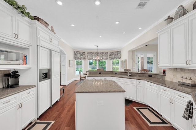 kitchen with a sink, white cabinets, a peninsula, crown molding, and recessed lighting