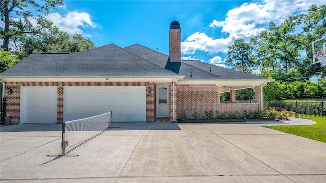 view of front of home featuring driveway, an attached garage, brick siding, fence, and a chimney