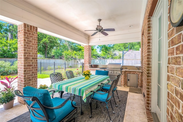 view of patio / terrace featuring exterior kitchen, fence, outdoor dining space, a ceiling fan, and a grill