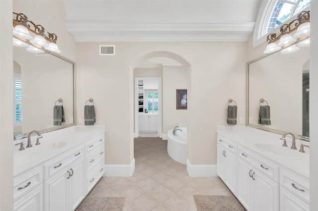 full bathroom featuring ornamental molding, two vanities, plenty of natural light, and a bathtub