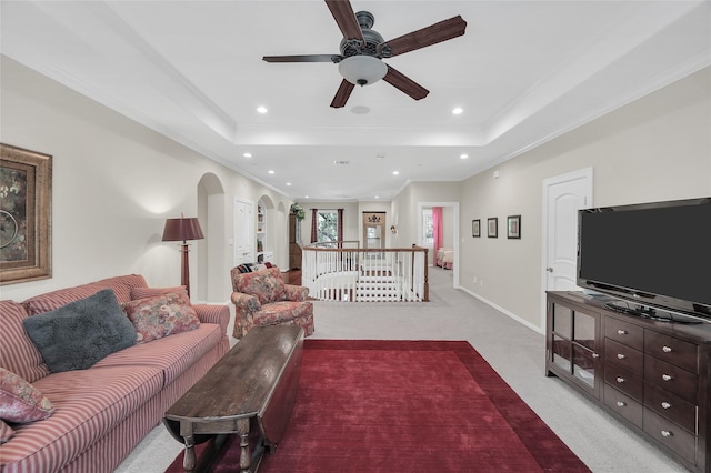 living room featuring arched walkways, a tray ceiling, light carpet, a ceiling fan, and recessed lighting