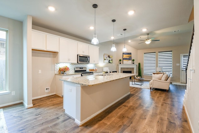 14923 Cutleaf Ln, Cypress, TX 77429 - kitchen with stainless steel appliances, open floor plan, white cabinets, a tiled fireplace, and a ceiling fan