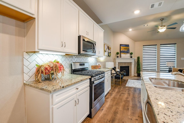 14923 Cutleaf Ln, Cypress, TX 77429 - kitchen featuring stainless steel appliances, lofted ceiling, ceiling fan, decorative backsplash, and white cabinetry