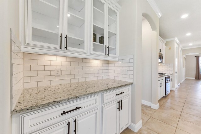 19115 Blooms Rise Dr, Tomball, TX 77377 - kitchen featuring arched walkways, crown molding, stainless steel appliances, white cabinetry, and light stone counters