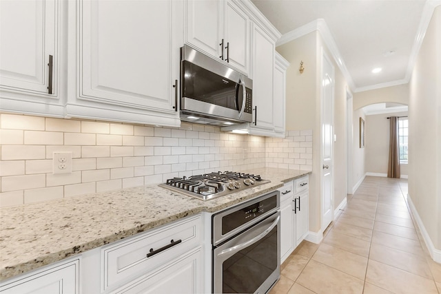 19115 Blooms Rise Dr, Tomball, TX 77377 - kitchen featuring stainless steel appliances, arched walkways, crown molding, light tile patterned floors, and white cabinetry