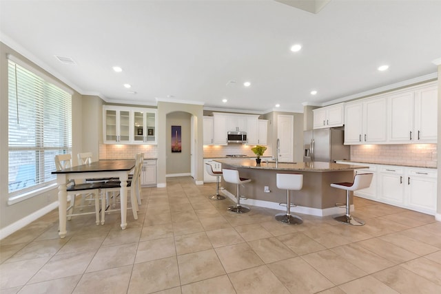 19115 Blooms Rise Dr, Tomball, TX 77377 - kitchen featuring appliances with stainless steel finishes, tasteful backsplash, ornamental molding, a kitchen bar, and an island with sink