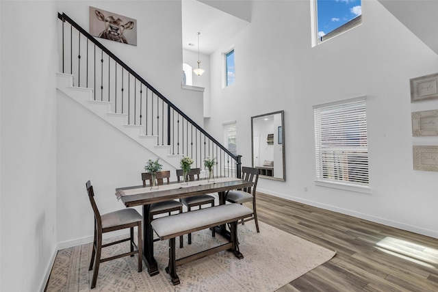 12311 Summerbrook Dr, Houston, TX 77066 - dining room featuring a towering ceiling, baseboards, wood finished floors, stairway, and a chandelier