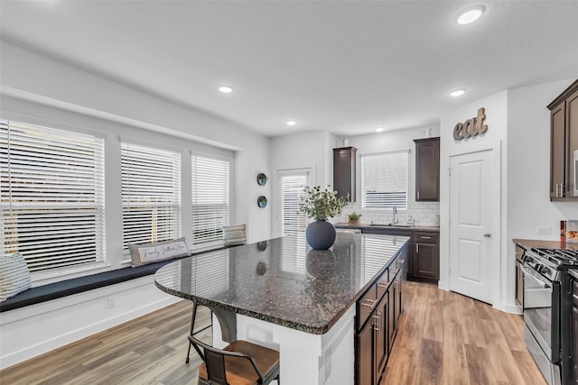 12311 Summerbrook Dr, Houston, TX 77066 - kitchen with gas stove, a sink, light wood-type flooring, dark brown cabinets, and a breakfast bar