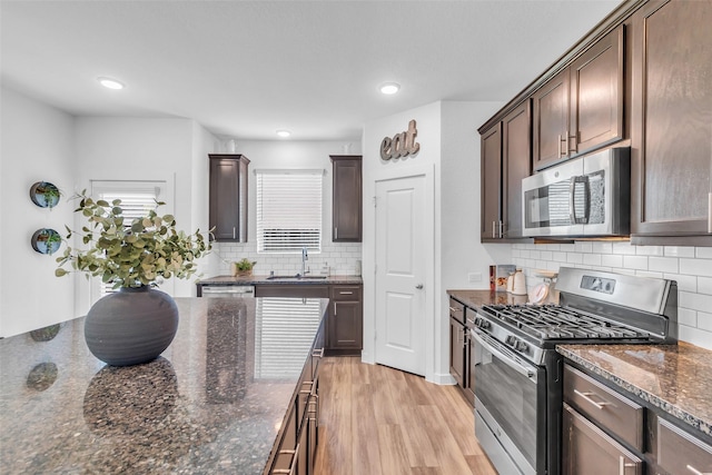12311 Summerbrook Dr, Houston, TX 77066 - kitchen featuring appliances with stainless steel finishes, dark brown cabinets, decorative backsplash, dark stone counters, and light wood-type flooring