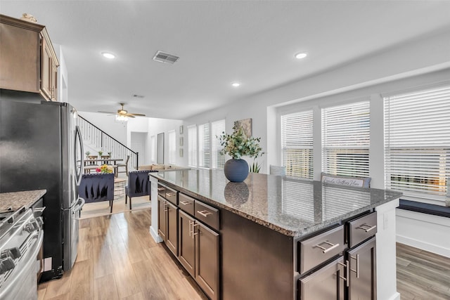 12311 Summerbrook Dr, Houston, TX 77066 - kitchen featuring stainless steel appliances, ceiling fan, light wood finished floors, a kitchen island, and dark stone counters