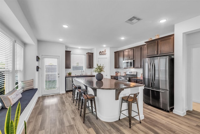 12311 Summerbrook Dr, Houston, TX 77066 - kitchen with appliances with stainless steel finishes, a breakfast bar area, dark brown cabinetry, a sink, and recessed lighting