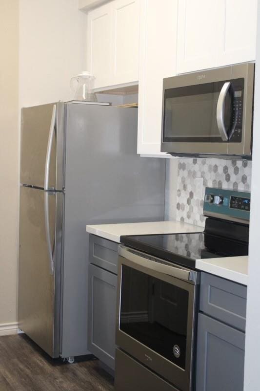 10049 Westpark Dr Unit 113, Houston, TX 77042 - kitchen with appliances with stainless steel finishes, gray cabinets, dark wood-style flooring, and light countertops