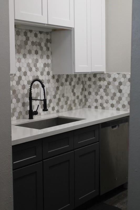 10049 Westpark Dr Unit 113, Houston, TX 77042 - kitchen featuring light countertops, backsplash, white cabinets, and stainless steel dishwasher