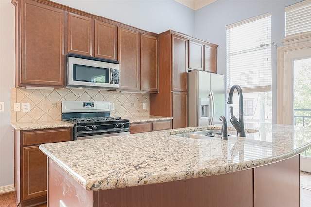 6014 Hamman St, Houston, TX 77007 - kitchen featuring stainless steel appliances, decorative backsplash, light stone counters, a center island with sink, and ornamental molding