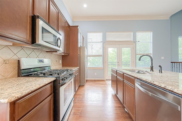 6014 Hamman St, Houston, TX 77007 - kitchen featuring appliances with stainless steel finishes, a sink, light wood-style flooring, crown molding, and tasteful backsplash