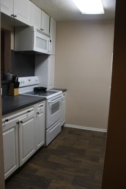 10047 Westpark Dr Unit 46, Houston, TX 77042 - kitchen featuring white appliances, dark countertops, white cabinets, a textured ceiling, and dark wood finished floors