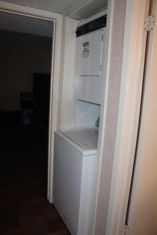 10047 Westpark Dr Unit 46, Houston, TX 77042 - laundry room with stacked washer / drying machine, dark wood-style floors, and a textured ceiling