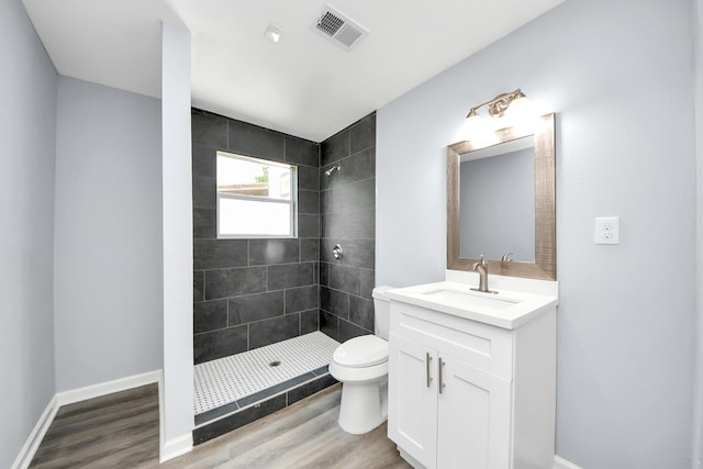 1707 Wilburn, Baytown, TX 77520 - bathroom with toilet, vanity, tiled shower, and wood finished floors