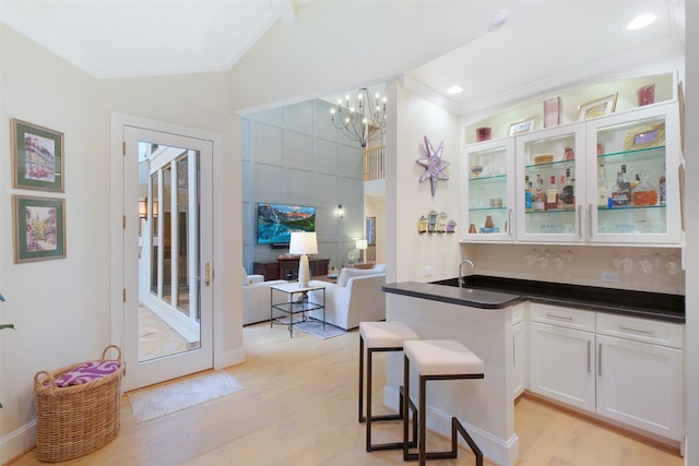 513 Rancho Bauer Dr, Houston, TX 77079 - kitchen with crown molding, white cabinets, light wood-style floors, glass insert cabinets, and vaulted ceiling