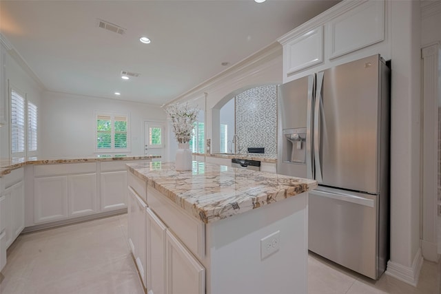 5411 Oban Terrace Ln, Sugar Land, TX 77479 - kitchen featuring stainless steel appliances, arched walkways, a kitchen island, light stone counters, and light tile patterned floors
