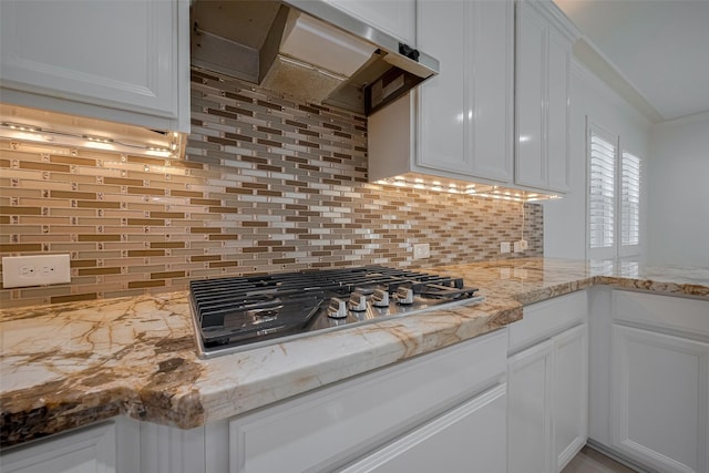 5411 Oban Terrace Ln, Sugar Land, TX 77479 - kitchen featuring under cabinet range hood, stainless steel gas stovetop, decorative backsplash, white cabinetry, and ornamental molding