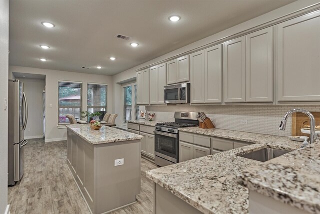 106 Emory Birch Dr, Montgomery, TX 77316 - kitchen with stainless steel appliances, a sink, a center island, decorative backsplash, and light wood-type flooring