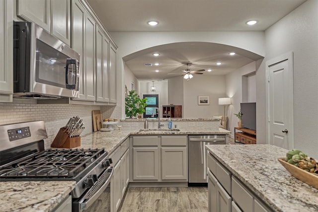 106 Emory Birch Dr, Montgomery, TX 77316 - kitchen featuring appliances with stainless steel finishes, a sink, arched walkways, a peninsula, and tasteful backsplash