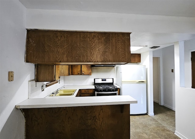 6315 Mardale Dr, Houston, TX 77016 - kitchen with stainless steel gas range oven, freestanding refrigerator, a peninsula, a sink, and light countertops