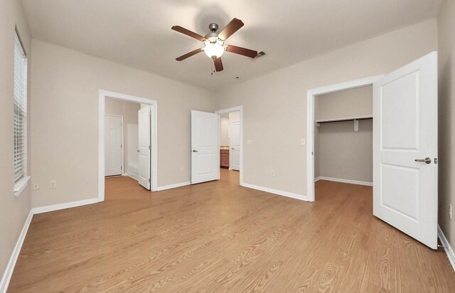5323 Menard Ave, Galveston, TX 77551 - unfurnished bedroom with light wood-style floors, a walk in closet, baseboards, a closet, and ceiling fan