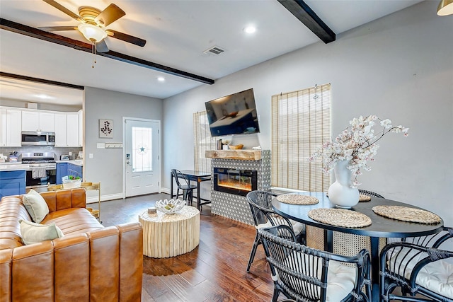 3108 Rogers St, Houston, TX 77022 - living room featuring beam ceiling, a glass covered fireplace, a ceiling fan, dark wood finished floors, and baseboards