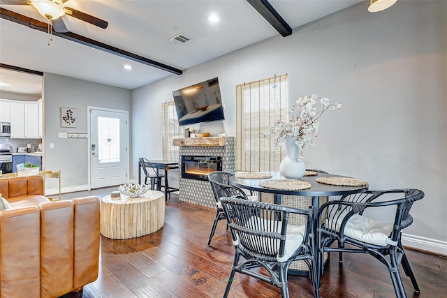 3108 Rogers St, Houston, TX 77022 - dining space featuring beamed ceiling, a glass covered fireplace, baseboards, ceiling fan, and dark wood finished floors