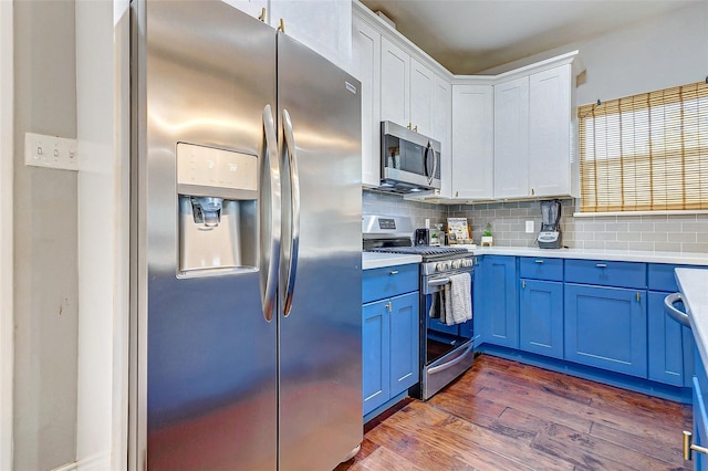 3108 Rogers St, Houston, TX 77022 - kitchen featuring stainless steel appliances, blue cabinetry, decorative backsplash, dark wood finished floors, and light countertops