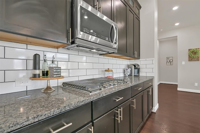 10718 Winding Green Dr, Humble, TX 77338 - kitchen featuring appliances with stainless steel finishes, baseboards, decorative backsplash, dark stone countertops, and dark wood-style floors