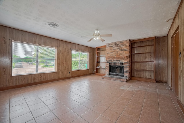 3619 Kilkenny Dr, Houston, TX 77047 - unfurnished living room with a ceiling fan, a textured ceiling, wood walls, a fireplace, and built in features