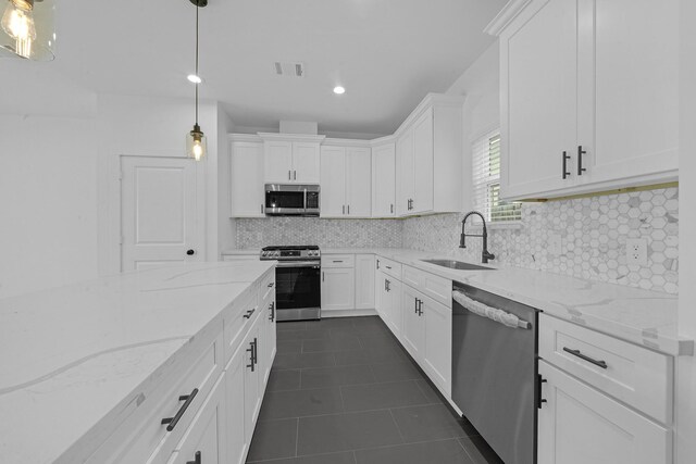 1515 Egypt St, Houston, TX 77009 - kitchen with stainless steel appliances, a sink, dark tile patterned flooring, white cabinets, and decorative backsplash